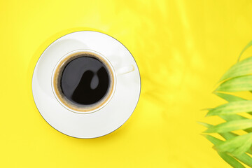 Aromatic coffee in cup on yellow table, top view. Space for text