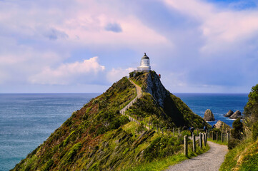 Nugget Point New Zealand a scenic lighthouse atop a cliff along a winding coastal trail