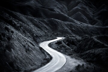 A grey winding road curves through a rugged mountain landscape