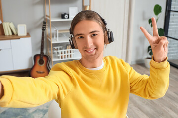 Young man in headphones taking selfie at home