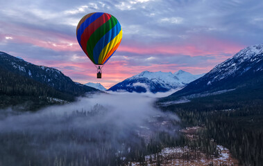 Fototapeta premium Colorful Hot Air Balloon Over Snowy Mountains At Sunset In Misty Valley