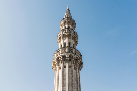 Tall mosque minaret against a clear blue sky with copy space.