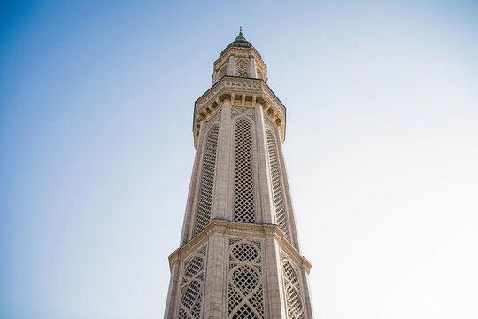 Tall mosque minaret against a clear blue sky with copy space.