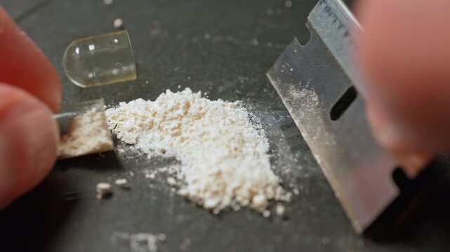 Drug dealer packing powdered synthetic opioid drug fentanyl in the gelatin capsule concept. Toxic drug crisis. Drugs for distrubution on the streets or parties.