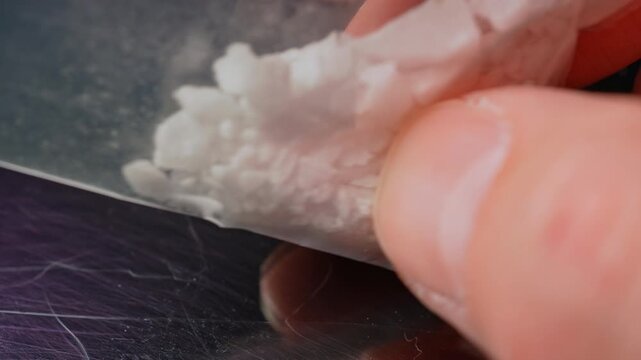 Synthetic opioid crystals like fentanyl or nitazenes drugs in clear plastic bag held in hands of drug user concept.