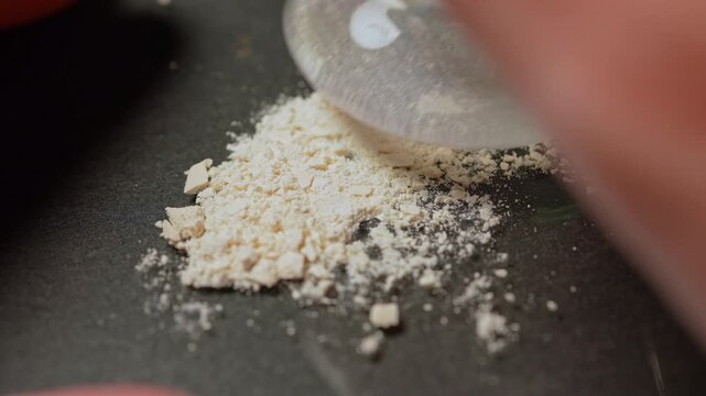 Clandestine chemist using mortar and pestle crushing prescription opioid drug to mix with fentanyl concept. Illegal drug laboratory mixing synthetic opioids for distribution.