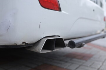 Close-up of white car exhaust pipe on brick road