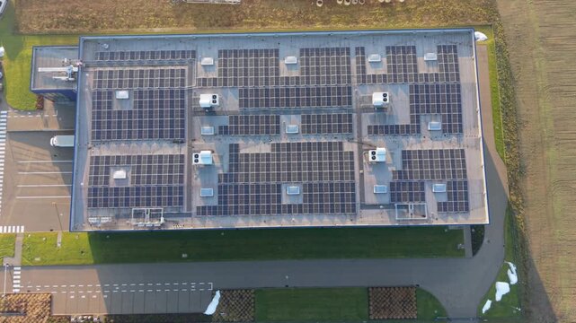 Aerial View Commercial Rooftop Solar Array, Dense Photovoltaic Panels Covering Roof Surface, Inverters And Mounting Rails Visible, Sunlight Reflection And Clean Energy Installation