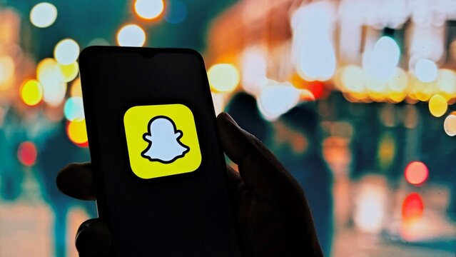Hand holding smartphone with Snapchat logo at night
