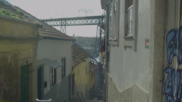 Narrow street in Porto old town with Dom Luis I Bridge visible ahead.