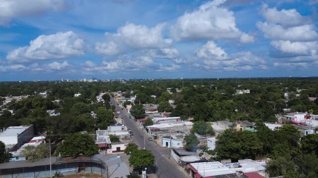 Drone 4K aerial view showing a residential urban area embedded within dense tropical greenery. Streets and homes coexist with natural vegetation, illustrating the relationship between everyday urban l