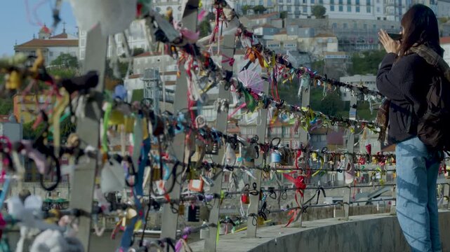 Close-up of colorful love locks attached to a metal fence in an urban setting. Love locks attached to a bridge railing with city view in the background.