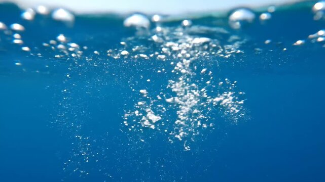 Underwater Bubbles - This video captures a vibrant underwater scene with numerous white bubbles rising towards the surface. The water is a deep blue hue, creating a sense of depth and clarity.