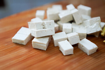 Diced white tofu cubes on wooden cutting board
