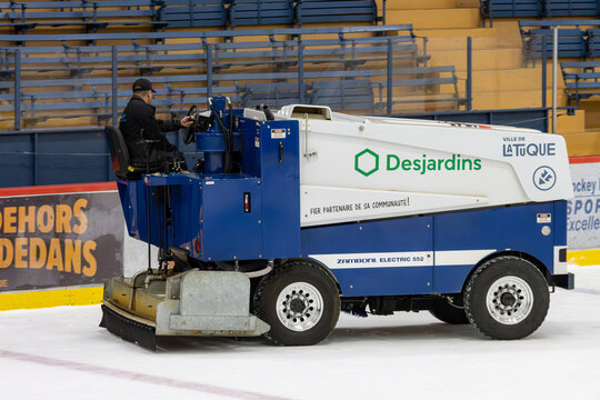 Canada, Quebec, 15 November 2025 : Man driving blue Zamboni ice resurfacer at empty hockey stadium