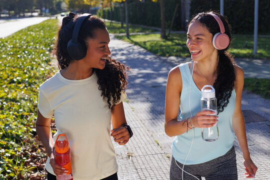 Women wearing headphones enjoying fitness walk together