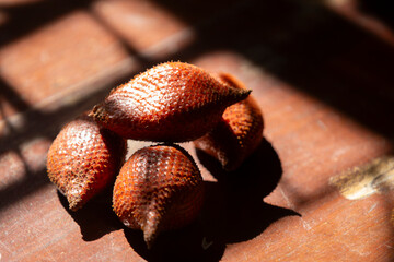 Salak fruit or snake fruits on the wooden table in the sunlight.