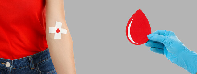 Donor with bandage and hand in glove hold decorative blood drop