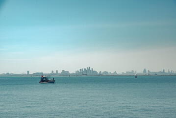 Small fishing boat in the sea with modern pattaya city skyline in background
