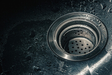 Water droplets on stainless steel kitchen sink drain strainer
