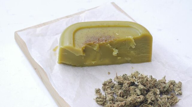 Close up shot of cannabis-infused butter (cannabutter) and a spatula on parchment paper, medicinal and edible marijuana concept.