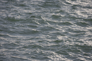 A wide-angle shot of the calm ocean with gentle ripples, extending to the horizon under a pale