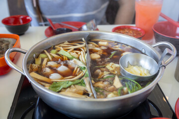 bubbling hot pot filled with a variety of ingredients, including vegetables, noodles, and meat.