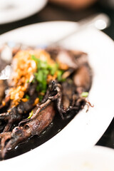 Stir fried black squid menu on the white dish, Thai food.