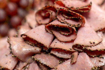 sliced pepper crusted cured beef pastrami arranged on a wooden board, showcasing gourmet deli meat texture, spices, and artisanal charcuterie ideal for food, restaurant, and culinary concepts