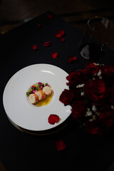 Fine dining plate of food with red roses. A delicious dish prepared with artistic presentation, a glass of wine, and rose petals