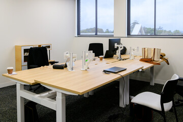 An open plan office featuring hot desks with computers - horizontal