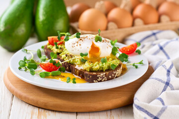 Breakfast with poached egg toast with avocado and tomatoes vegetarian food.