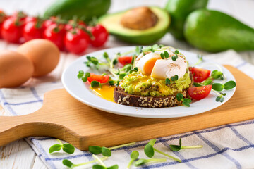Avocado toast with poached egg over rye bread toast with mashed avocado spread. Healthy breakfast or lunch food.