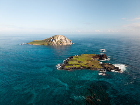 Aerial drone footage moving toward small tropical islands surrounded by clear blue ocean, showcasing rugged coastline, turquoise water, and remote island seascape in a peaceful natural environment