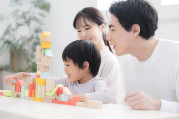 Obraz premium 積み木の前で幸せが伝わる笑顔のファミリー 教育や育児などの子育ての知育やチャレンジの家族イメージ 