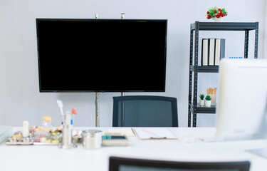 Interior of medical clinic office clean minimalist doctor workplace featuring blank presentation screen monitor supplies organized desk accessories shelving files plants bright hospital professional.