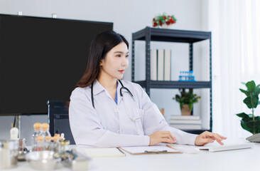 Portrait confident asian female doctor sitting working at desk in professional office medical clinic hospital using computer stethoscope documents system physician expertise in healthcare consultation
