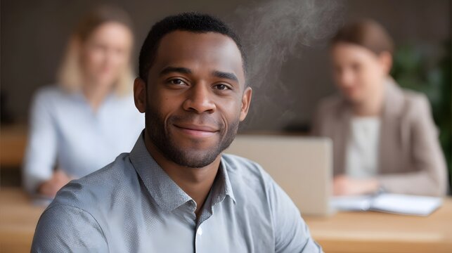 Professional man with a friendly smile in an office setting with blurred colleagues and rising steam