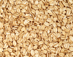 Full frame close-up of rolled oat flakes forming a dense cereal texture. Uncooked oats photographed from above with visible grain structure.
