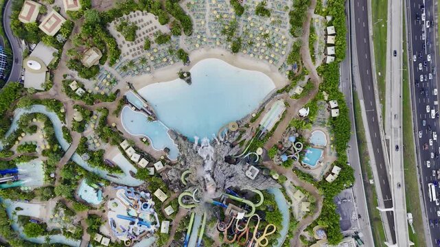 Aerial view of Volcano Bay water park with volcano, pools, slides and nearby highway traffic in Orlando, Florida, USA. g.