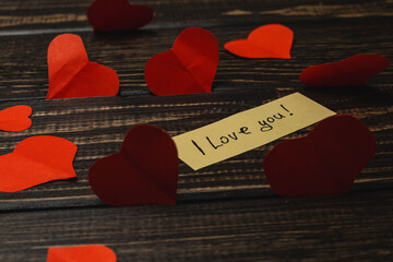 Red hearts and note on wooden table for love declaration