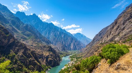 Obraz premium A dramatic river winds through towering canyon walls beneath a bright blue sky, rugged peaks embracing awe...