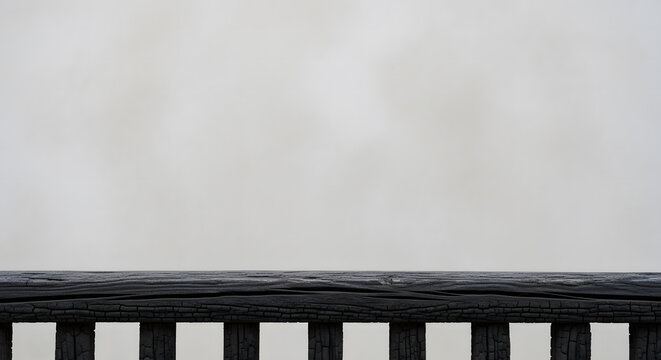 Close-up of dark charred wood fence railing texture against soft