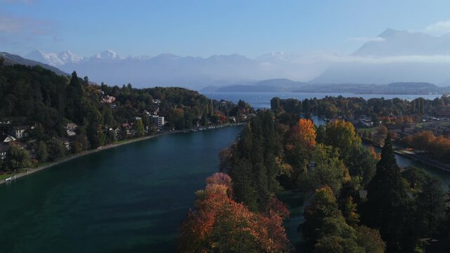 Thunersee Lake Thun Flusswelle Aare River aerial drone Thun Switzerland Schweiz Swiss Alps Fall Autumn sunny morning clouds haze Bernese Oberland Interlaken still water boats ferryforward pan up