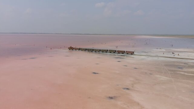 Burlinskoye Lake (Bursol), Altai Krai &mdash; Pink Salt Lake. A train‑like vehicle moves along the shore.