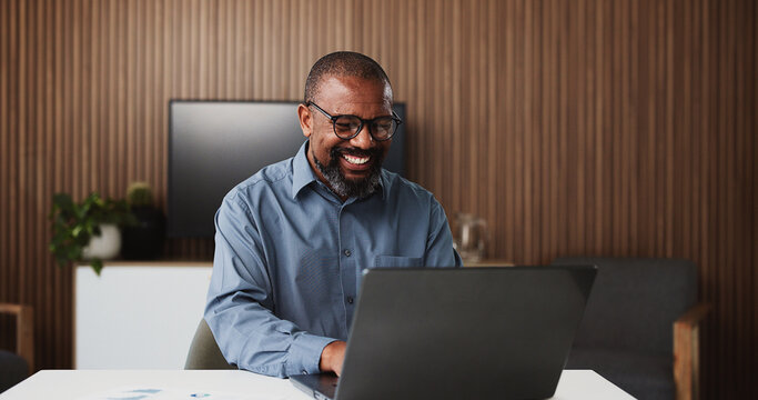 Laptop, lawyer and happy black man in office for research, proposal and success for case study. Professional, law firm and mature person on computer for information, legal review and winning trial