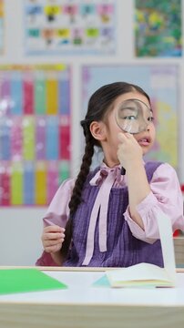 Young Girl Examining Objects With Magnifying Glass in Classroom
