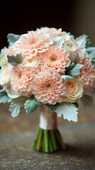 Beautiful bridal bouquet with peach flowers and green leaves arranged for a wedding ceremony indoors