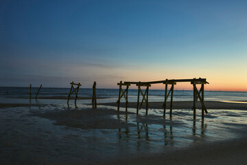 Fototapeta premium Silhouetted Pilings at Blue Hour Over Calm Coastal Water
