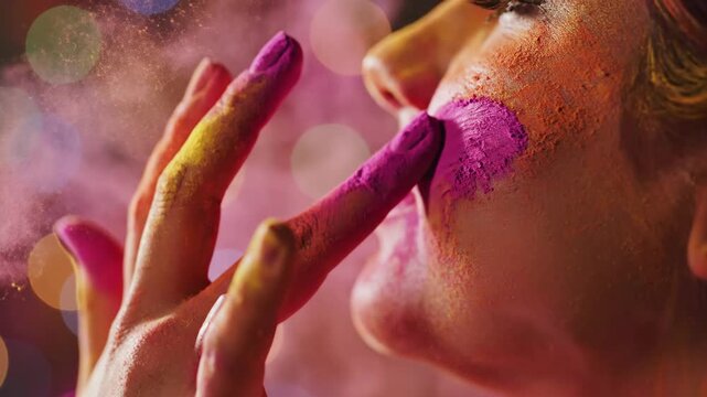 A happy person applies vibrant pink gulal to their cheek in a cinematic close-up during the colorful holi festival.